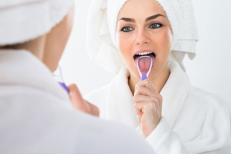 Woman using a tongue scraper to clean tongue