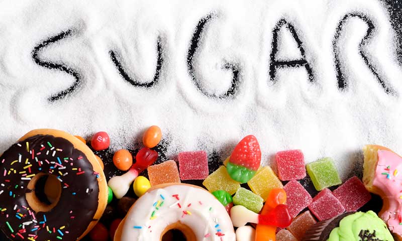 Donuts and candy with the word sugar written in pile of sugar