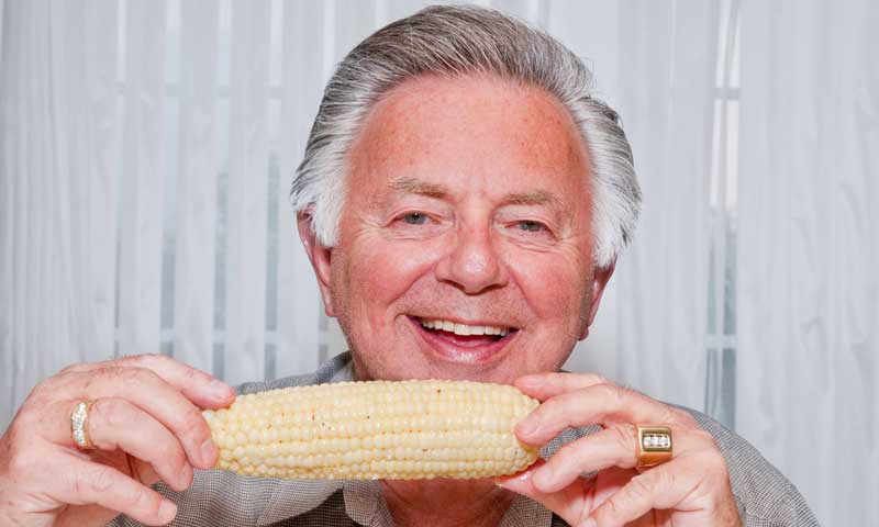 A man with new dental implants happy to be eating corn on the cob